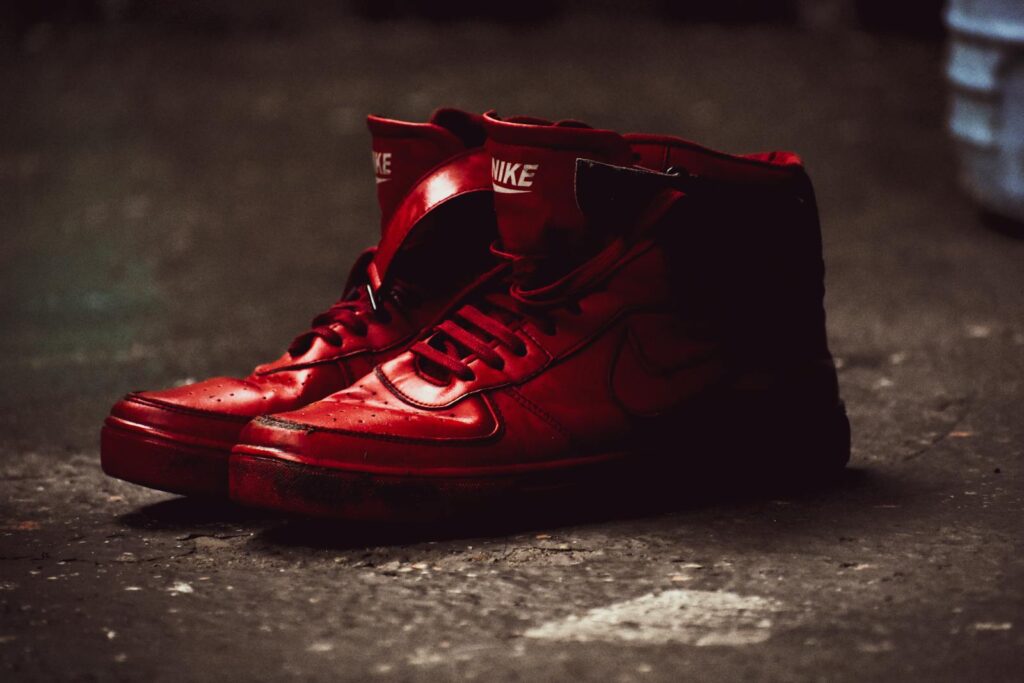 Close-up of red high-top sneakers on a gritty concrete backdrop, exuding street style.