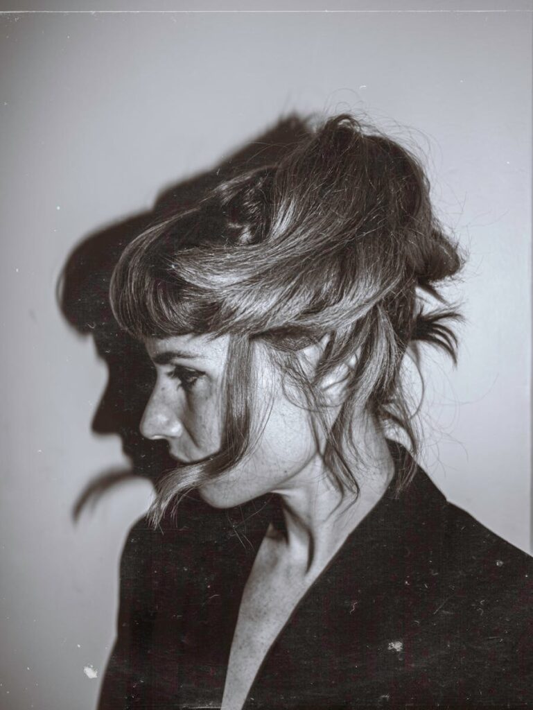 Grayscale portrait of a woman with messy hair and shadow profile.