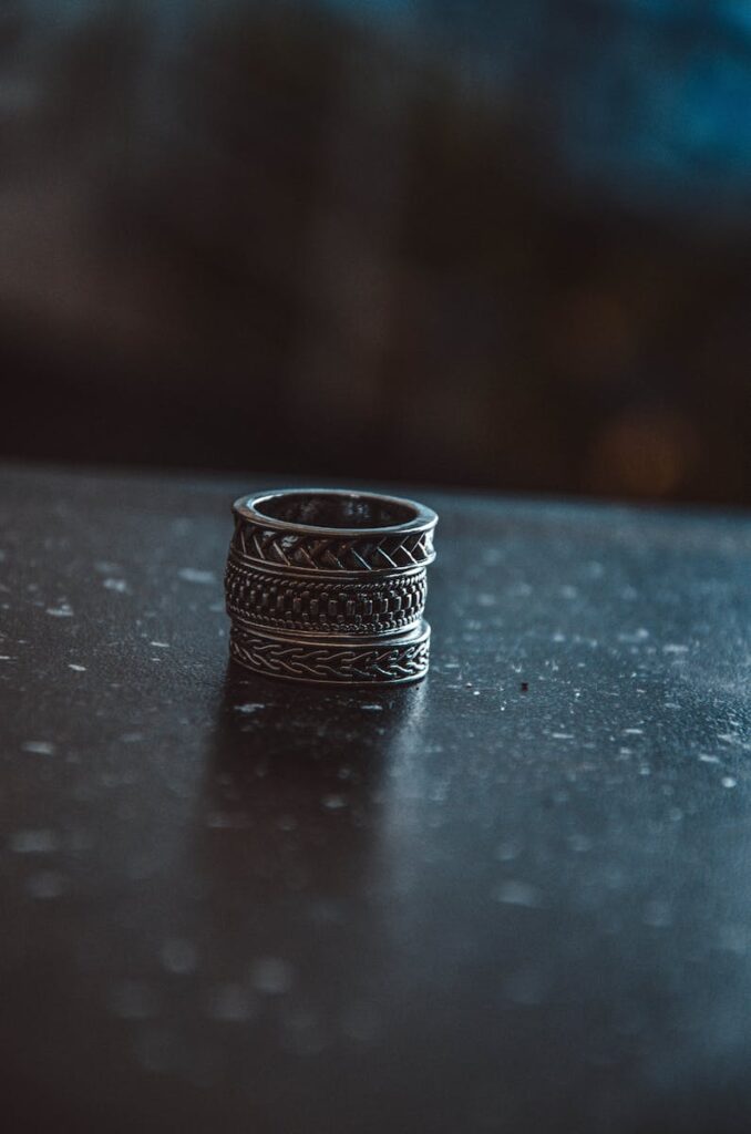 A detailed shot of intricate silver rings stacked on a dark table with a blurred background.