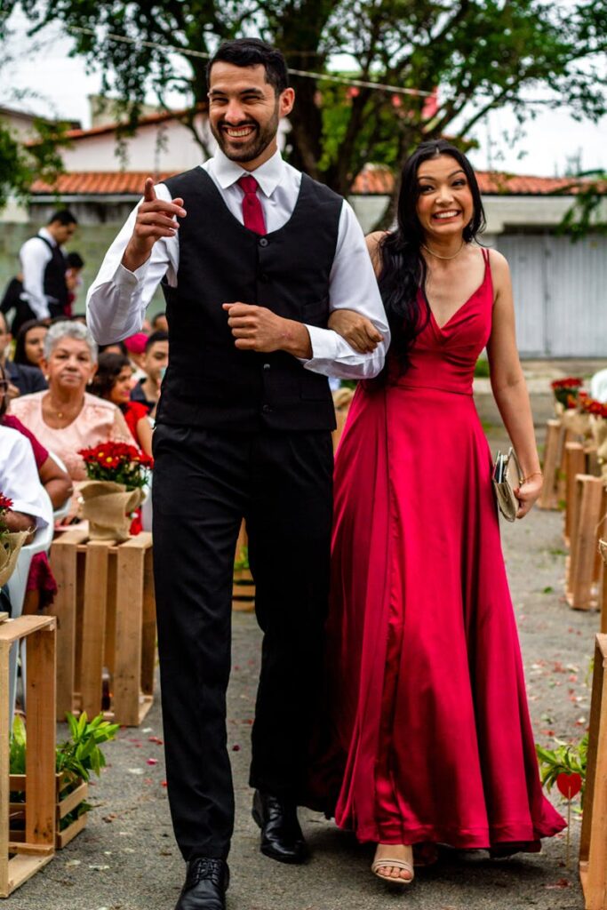 A joyful bridesmaid and groomsman walking down an outdoor wedding aisle in Pacatuba, CE, Brasil.