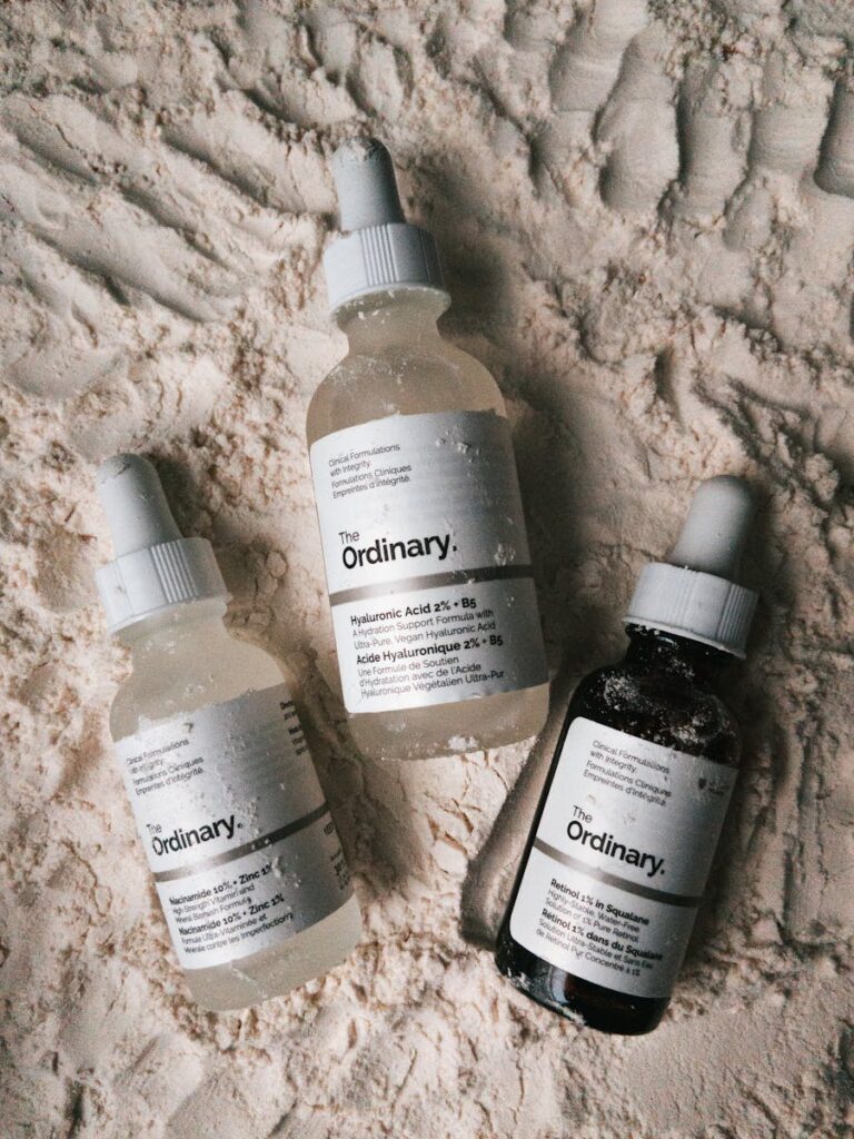 Three dropper bottles of The Ordinary serums displayed on a powdery surface.