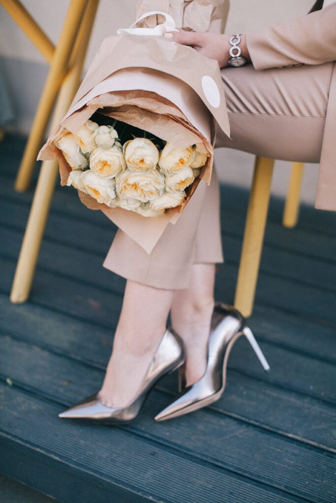 Chic fashion moment featuring a woman in metallic heels holding a bouquet of roses, highlighting elegance.