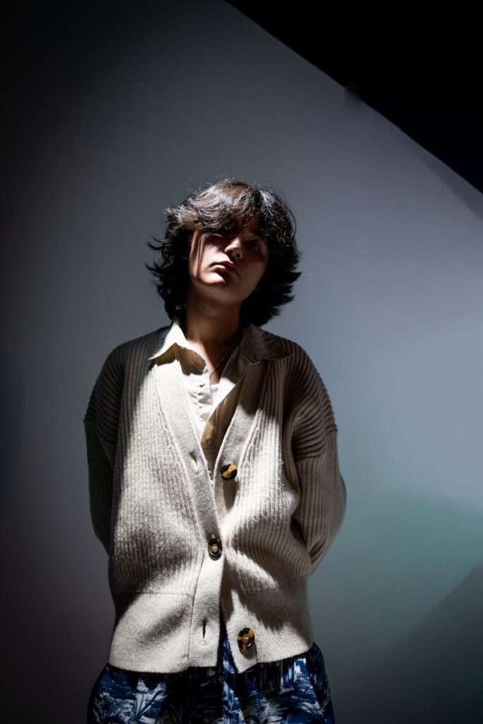 Eloquent studio portrait of a young model in elegant attire with dramatic lighting.