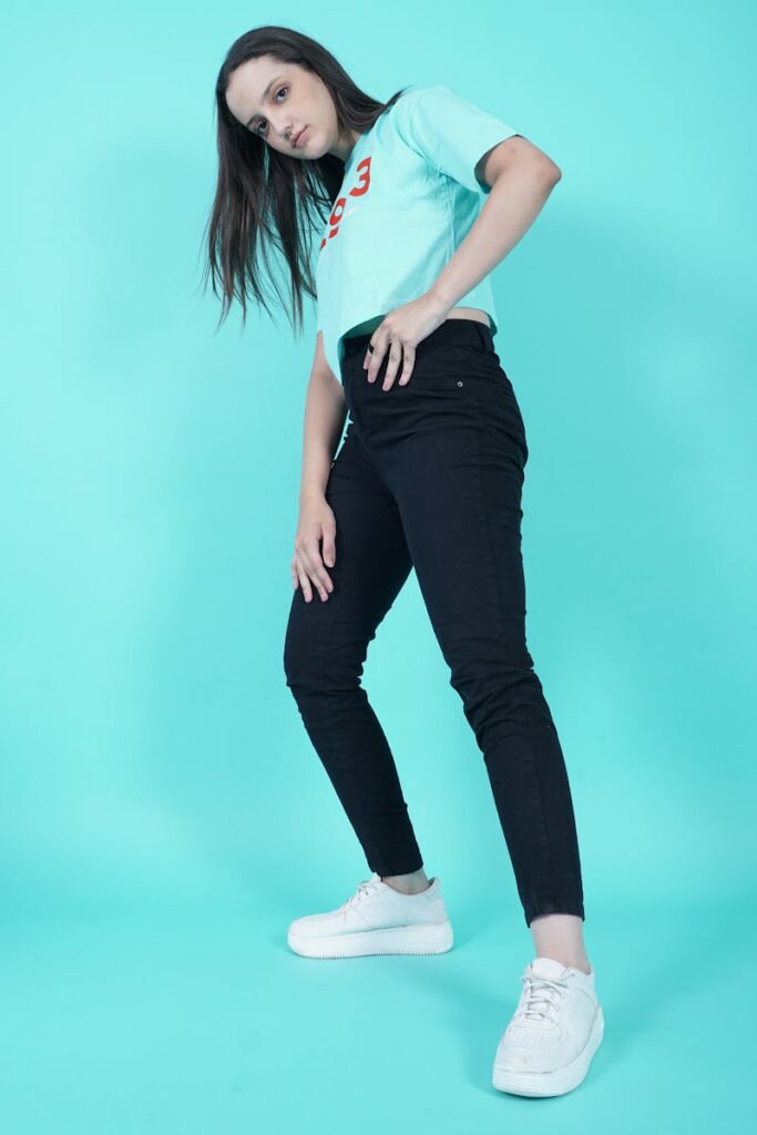 Model posing in casual outfit against a vivid aqua backdrop.