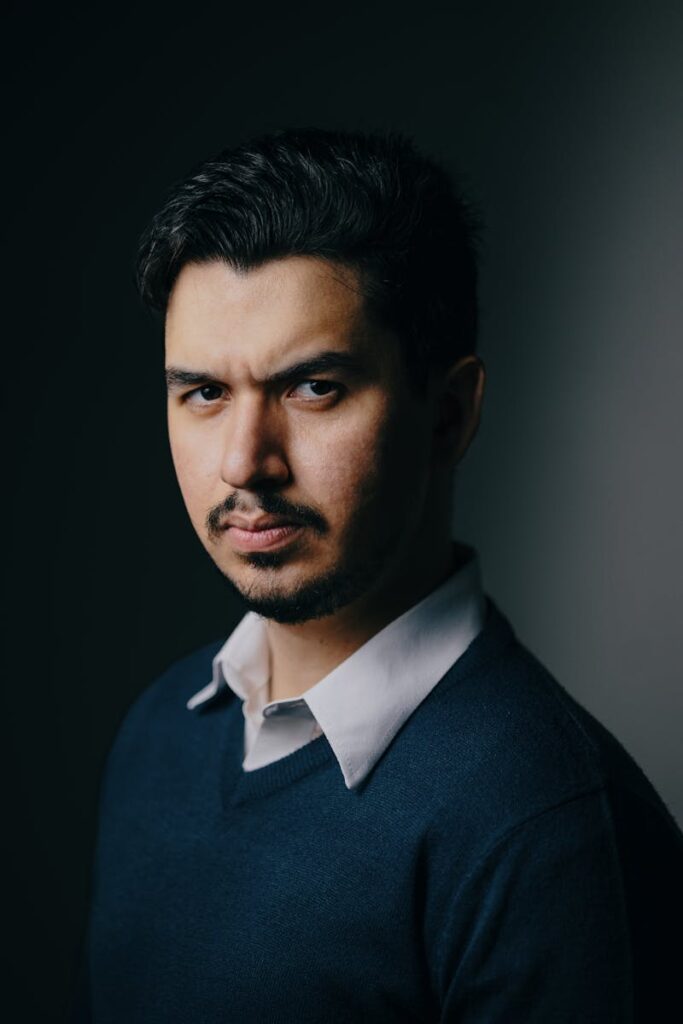 Focused portrait of a man in a dark setting, showcasing intense expression.