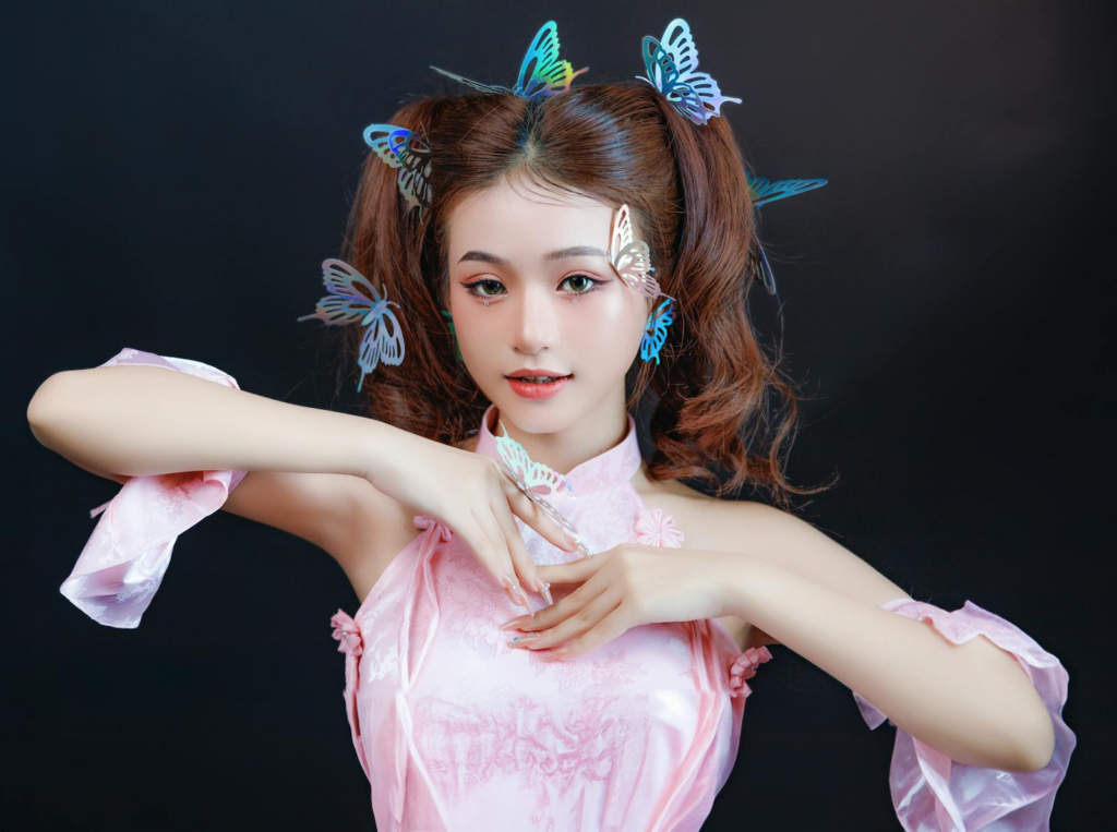 Elegant portrait of a young Asian woman wearing pink with butterfly hair clips, captured in a studio setting.