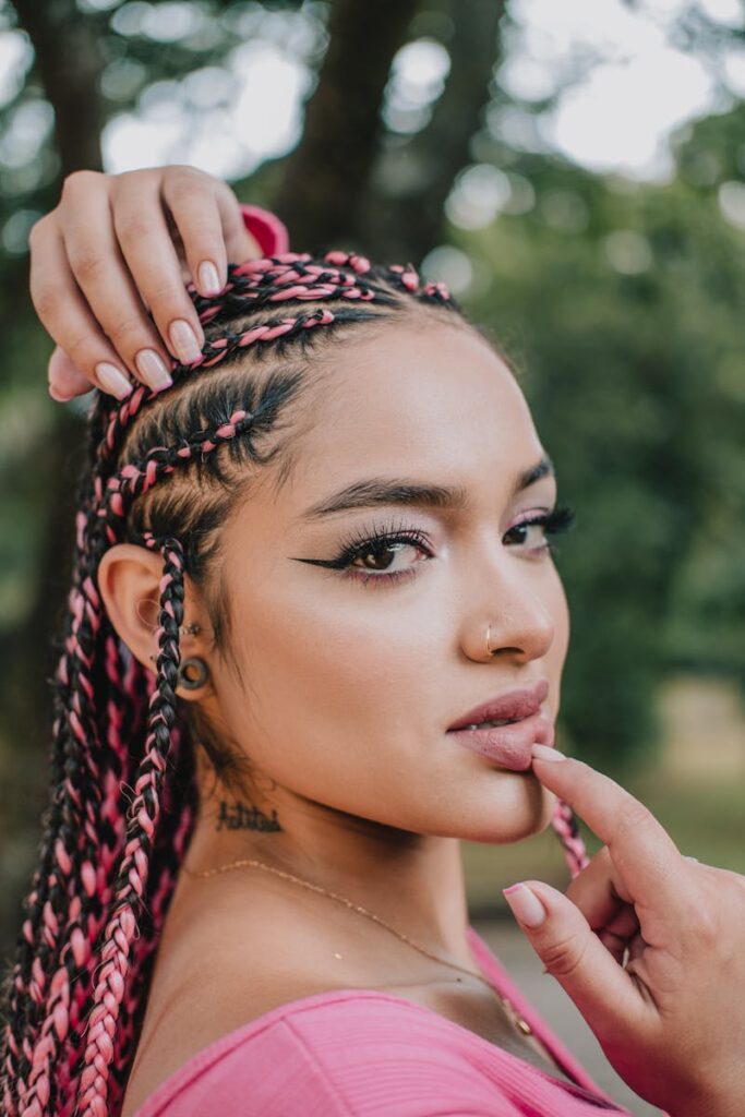 Stunning portrait of a woman with pink braids in a natural setting, showcasing beauty and style.
