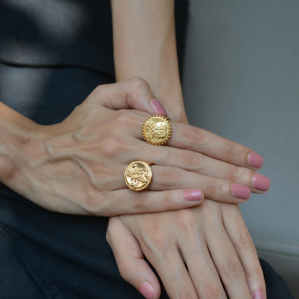 A close-up of hands wearing ornate gold rings showcasing elegance and style.