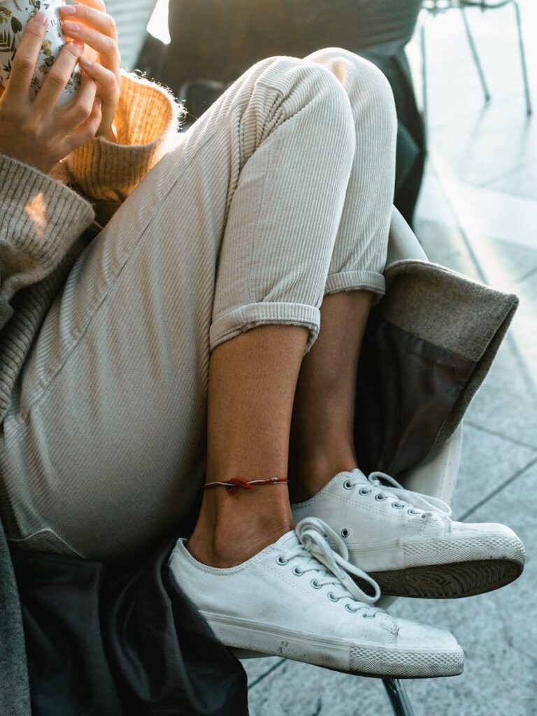 Close-up of a person sitting comfortably with white sneakers and a colorful anklet