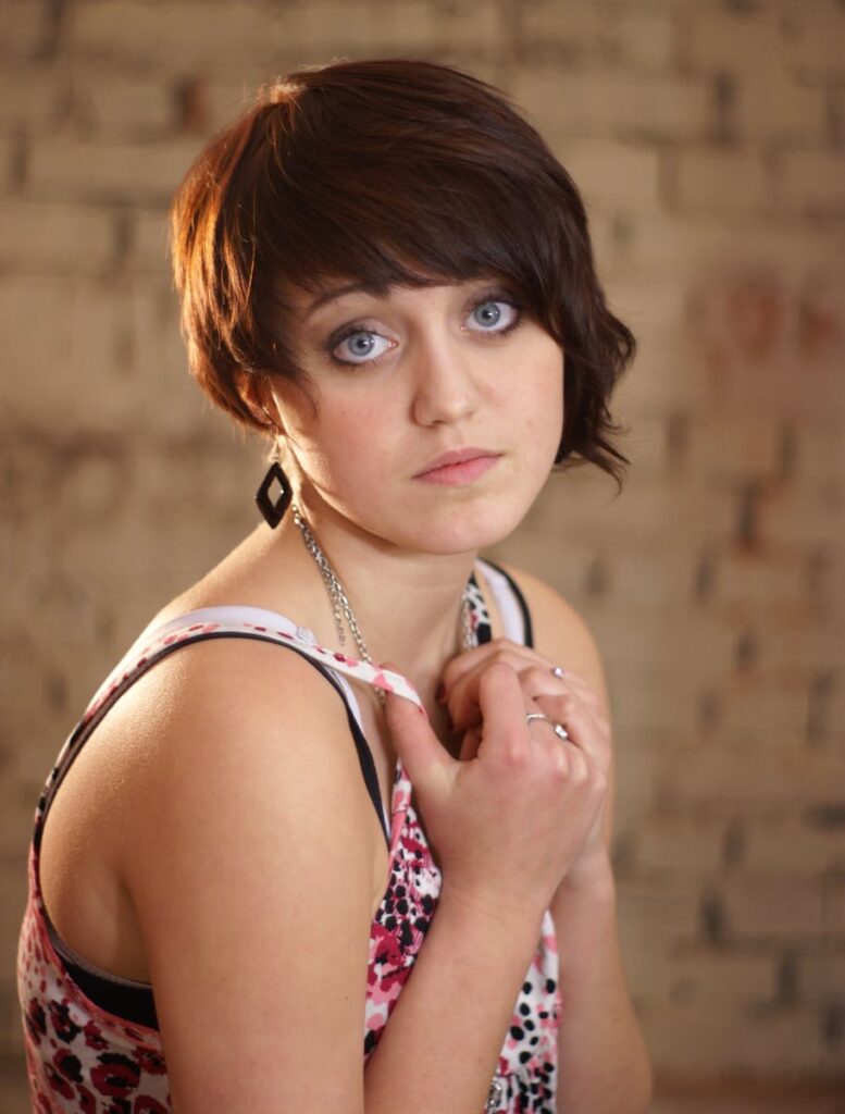 Elegant portrait of a fashionable woman with short hair posing indoors, wearing a patterned top.