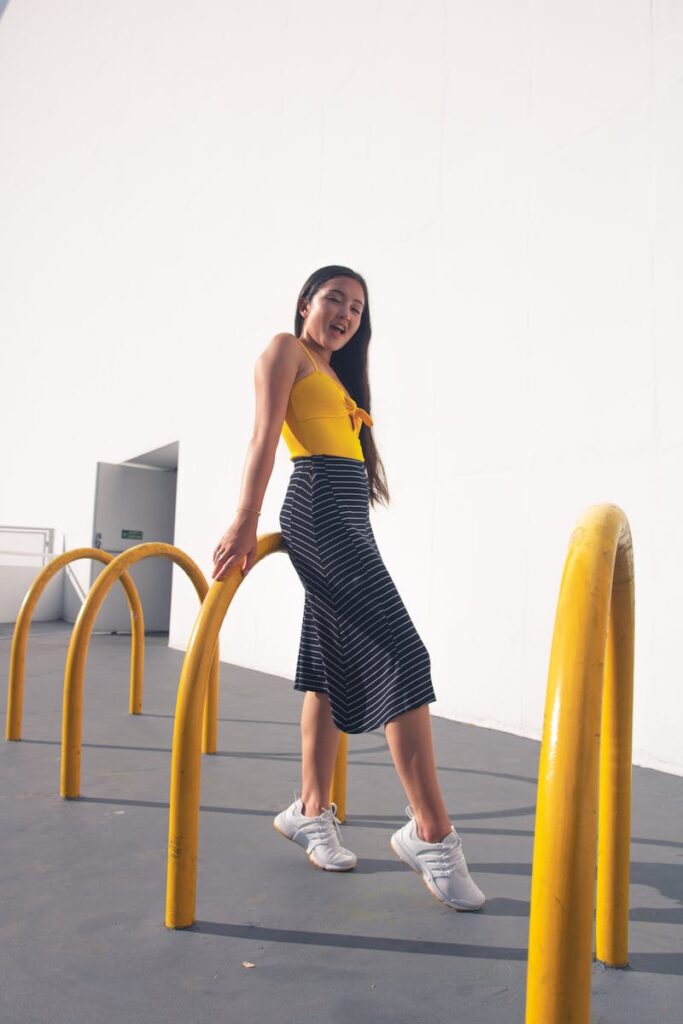 Smiling woman in a yellow top posing casually by a bike rack outdoors.