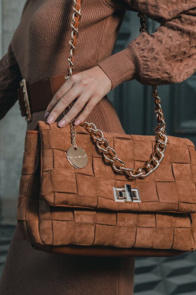 Elegant brown woven handbag with gold chain detail in a fashion shoot.