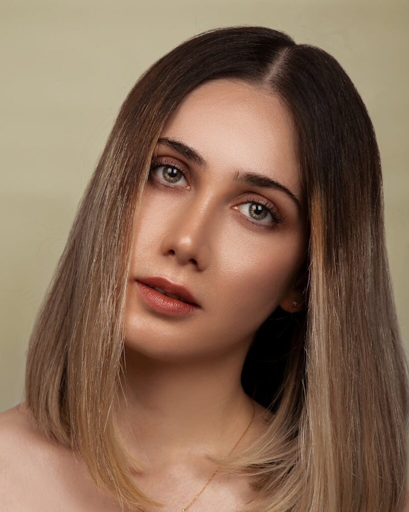 Elegant portrait of a young woman with natural makeup and long bob hairstyle in a studio setting.