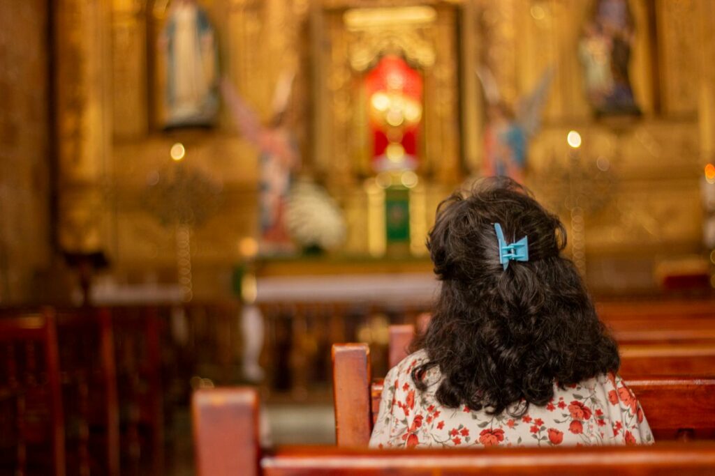 Back view of woman sitting inside a church in Barichara, Colombia, focusing on the altar.