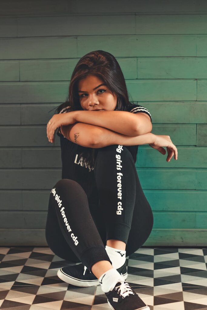 Fashionable young woman in casual attire sitting indoors. Trendy style and confident pose.