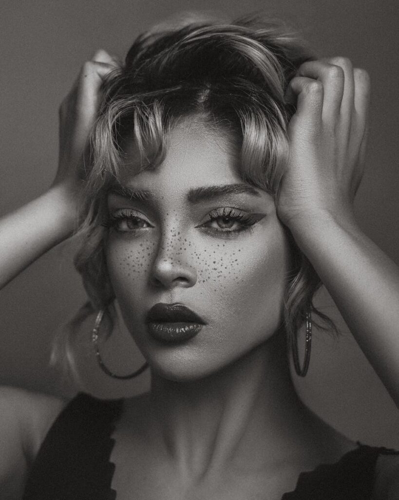 Captivating black and white portrait of a woman with blonde hair and bold makeup, showcasing classic beauty.