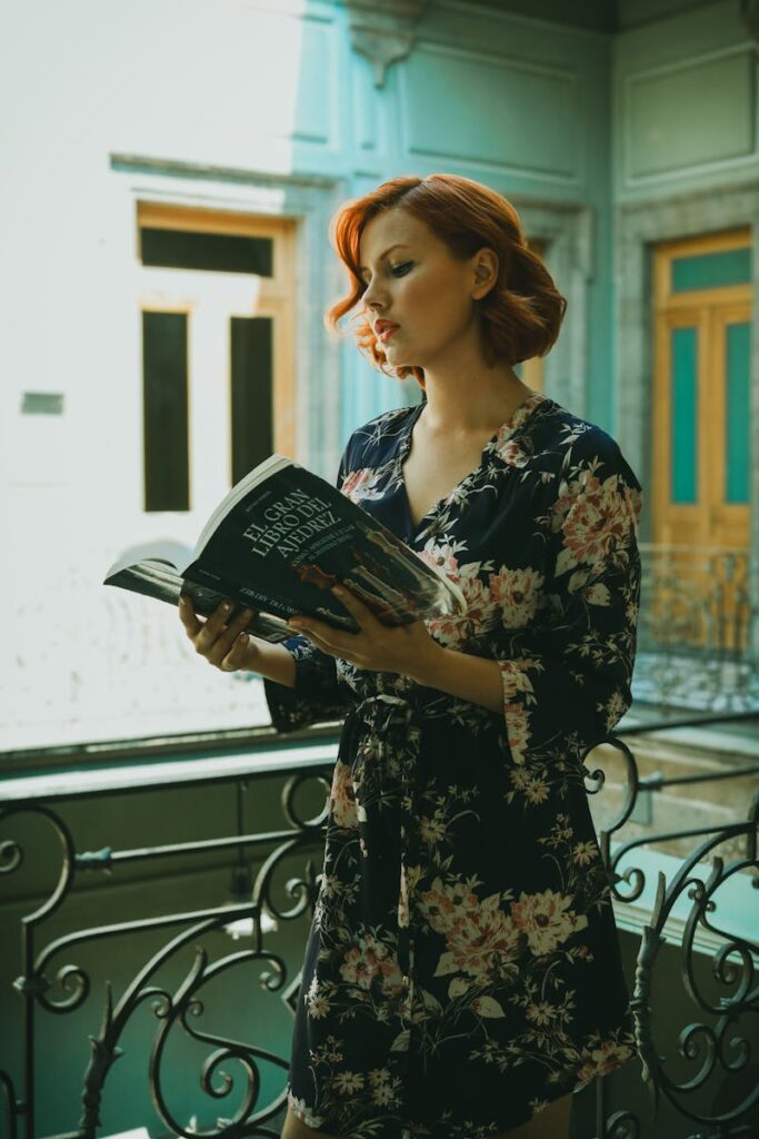 Elegant redhead woman reading a book on a balcony in Mexico City