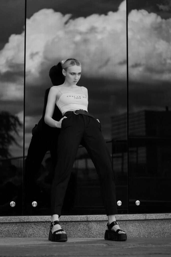 Artistic black and white fashion portrait of a woman posing with a dramatic reflection.