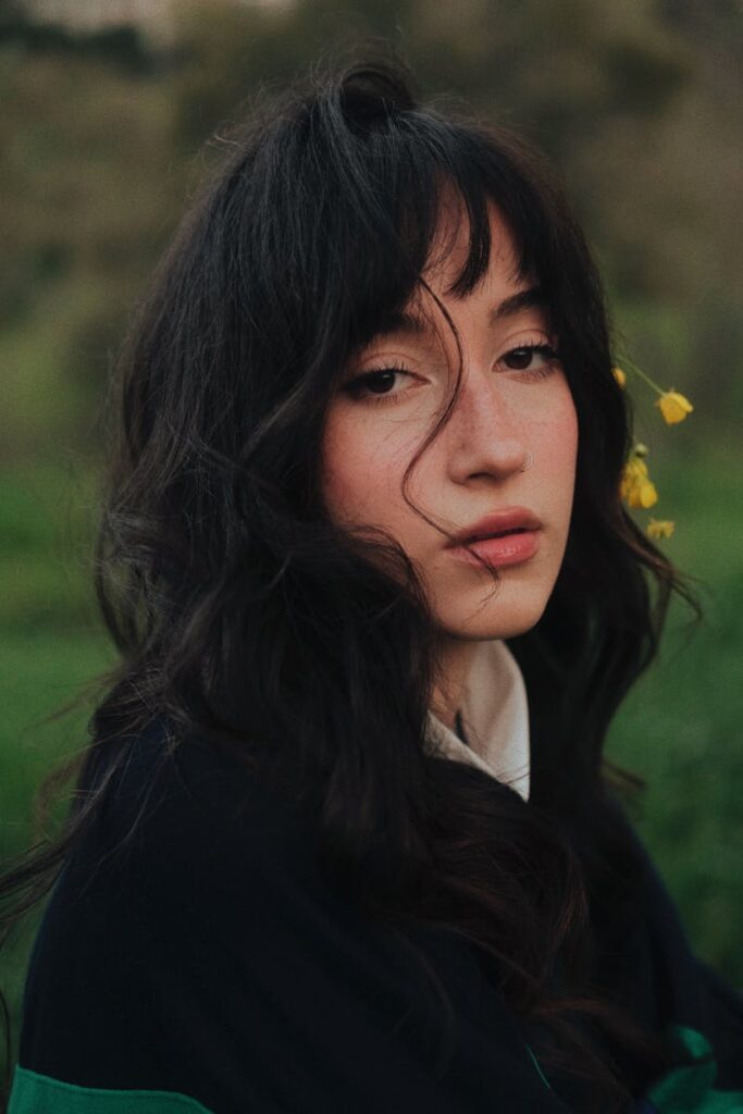 Portrait of a young woman with dark hair in a peaceful outdoor park during summer.