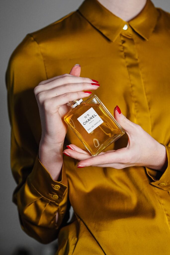 Close-up of a woman holding Chanel No.5 perfume bottle, showcasing luxury and elegance.