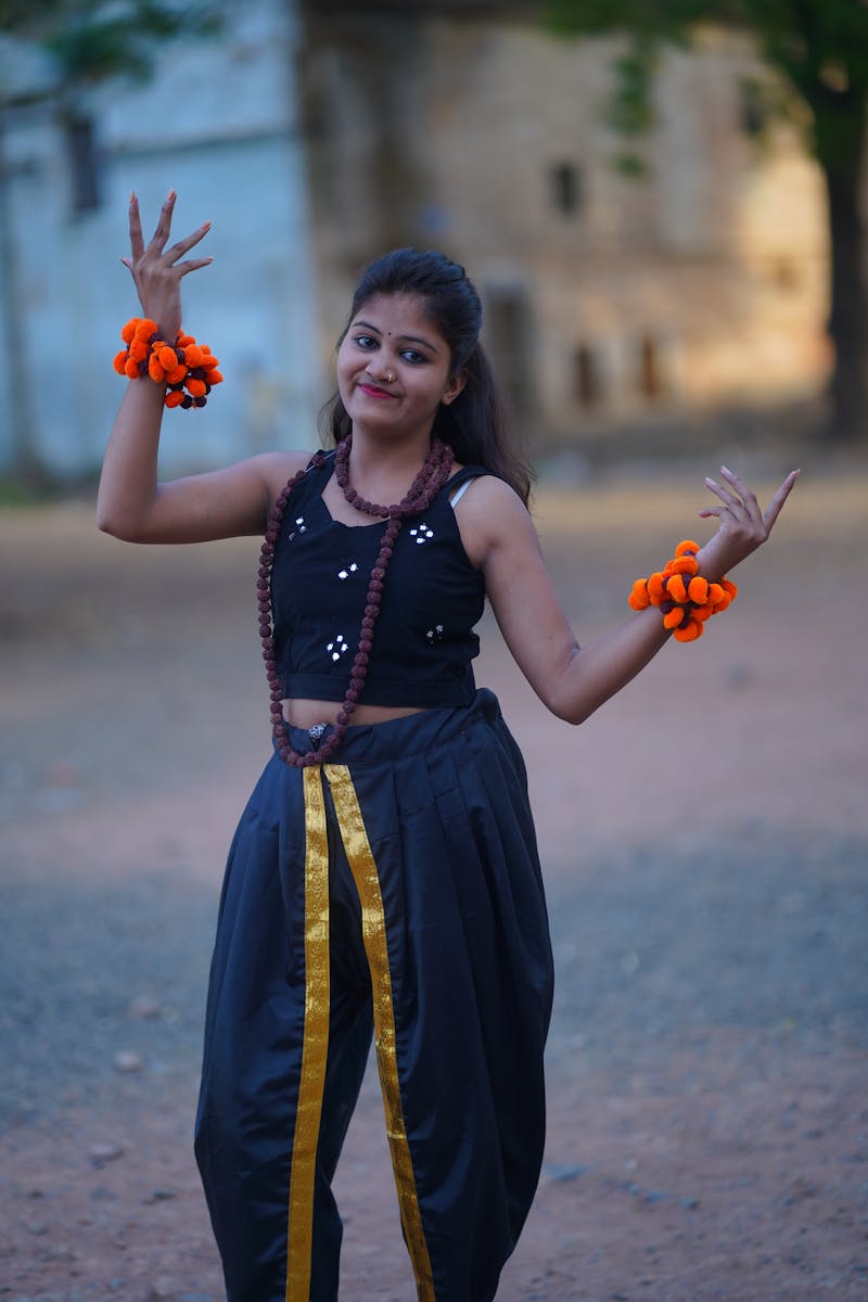 South Asian woman in traditional dance attire posing gracefully outdoors, showcasing vibrant cultural fashion.