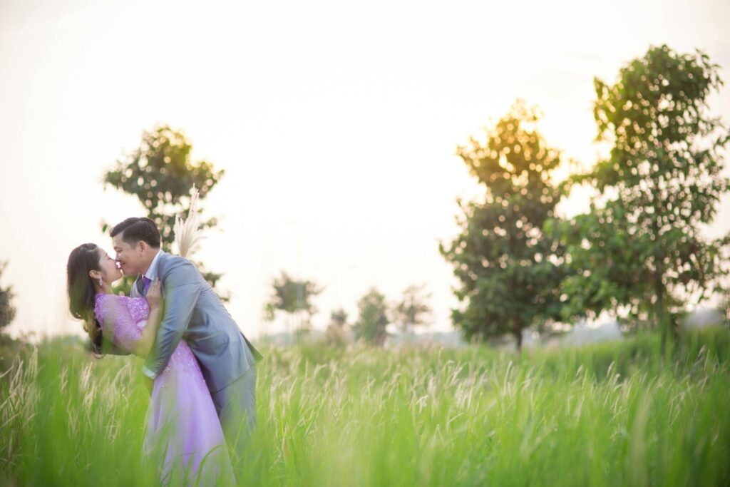 Couple embracing in a sunlit field, capturing a moment of love and romance.