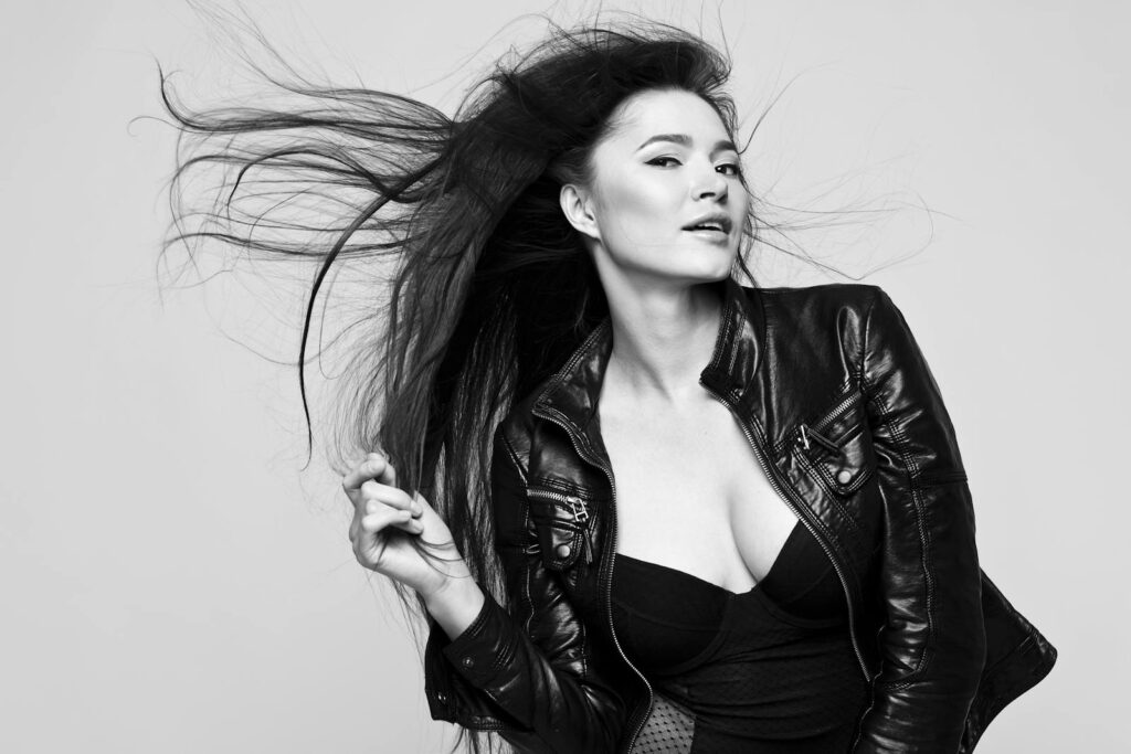 Elegant black and white portrait of a woman with flowing hair in a leather jacket.