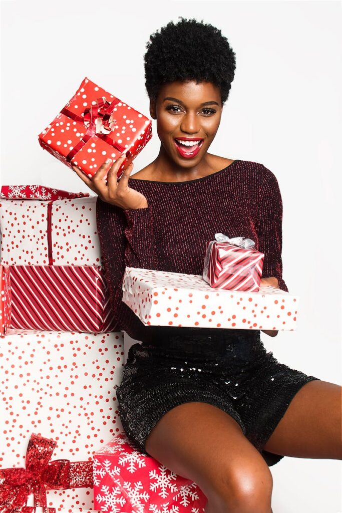 Joyful African American woman with Christmas presents, expressing excitement and holiday cheer.