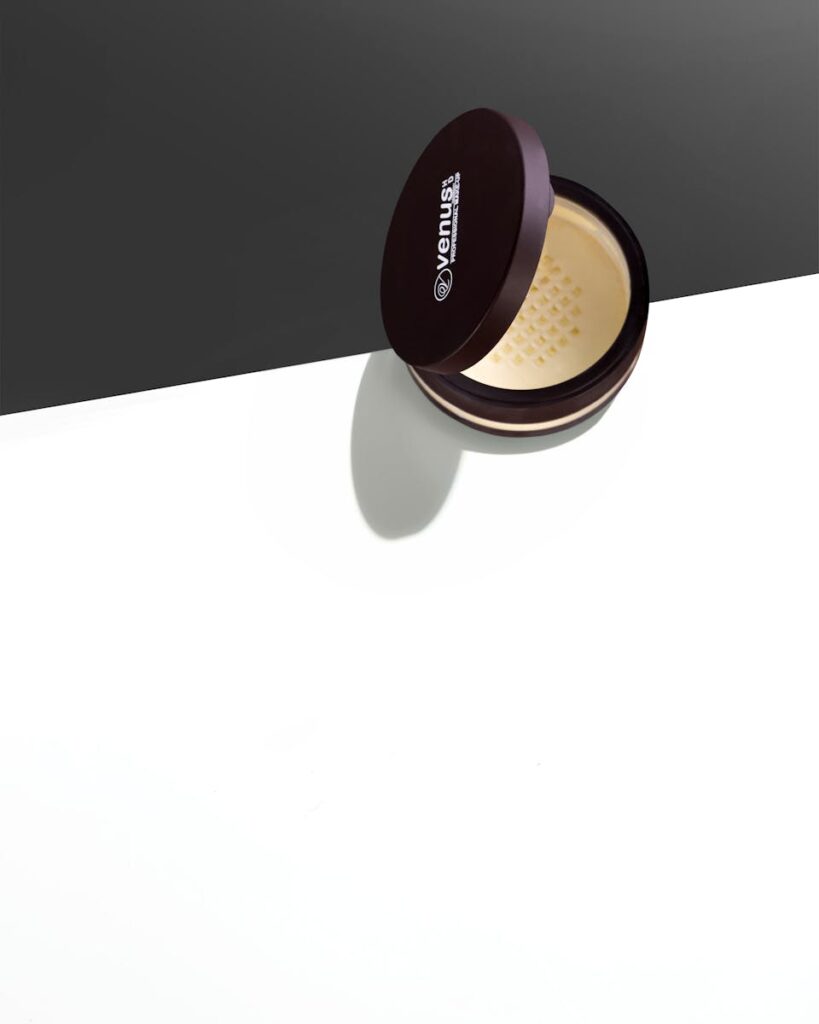 Elegant presentation of a cosmetic powder container on a stark black and white surface, showcasing minimalist design.