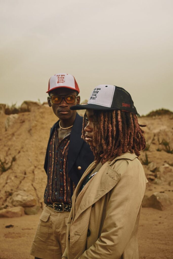 Two stylish adults wearing hats in a desert landscape at sunset.
