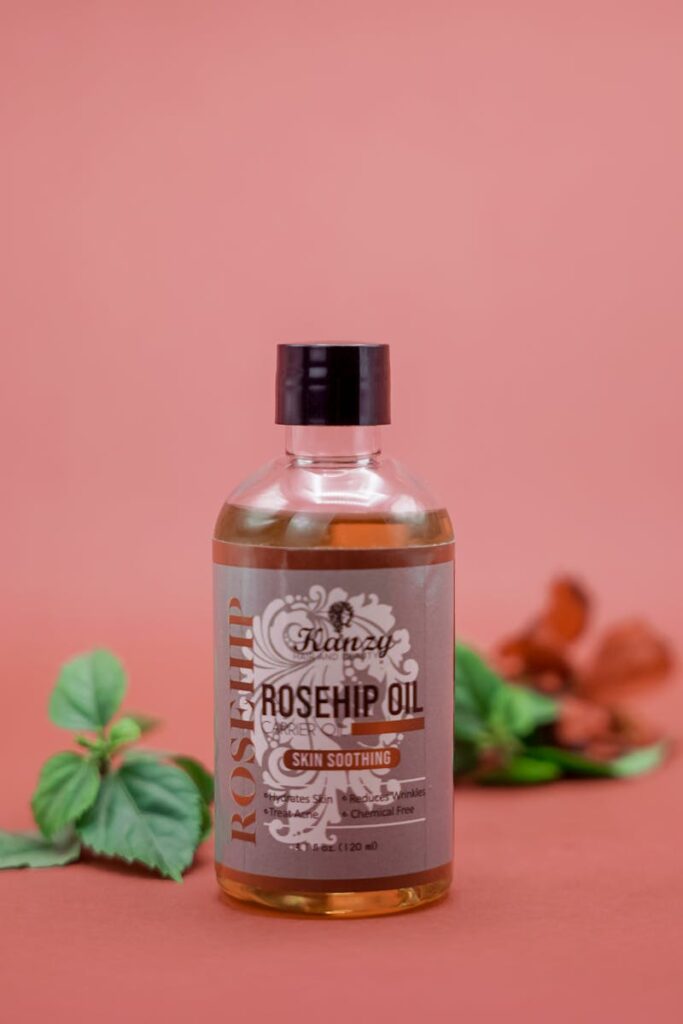 A still life image featuring a Karey rosehip oil bottle surrounded by leaves on a warm background.
