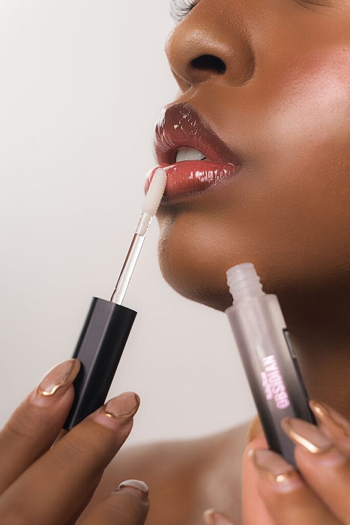 Detailed close-up of a black woman applying lip gloss, showcasing beauty and self-care.