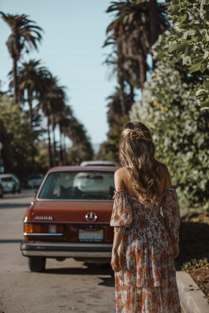 Stylish woman in floral dress strolling a palm-lined Los Angeles street.