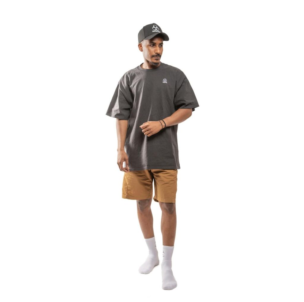 Full-body view of a man wearing casual streetwear with an oversized t-shirt and cap.