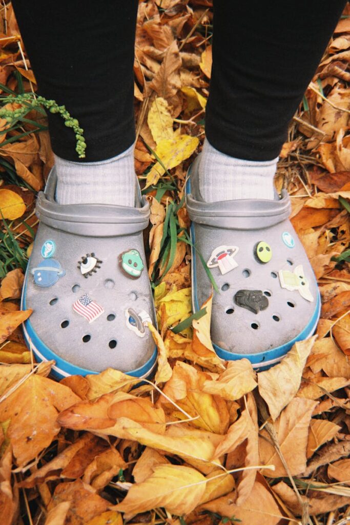 Gray Crocs adorned with pins on a bed of vibrant autumn leaves in Talgar.