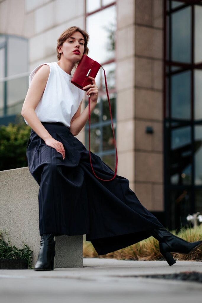 Fashionable woman sitting outdoors with red purse in Cologne.