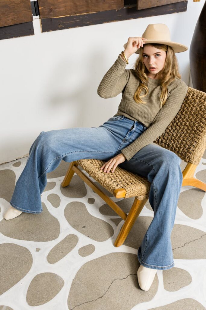 Young woman wearing a hat and casual outfit sitting stylishly indoors.