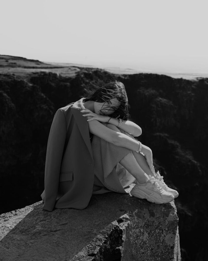 A woman in solitude sits peacefully on a clifftop in Armenia, enjoying a serene moment.