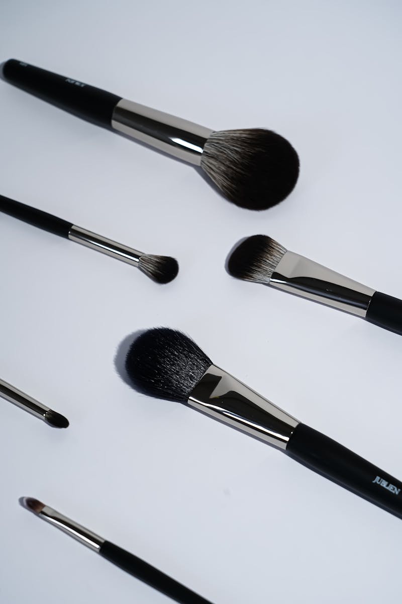 Flat lay of various makeup brushes arranged on a white surface, ideal for beauty concepts.