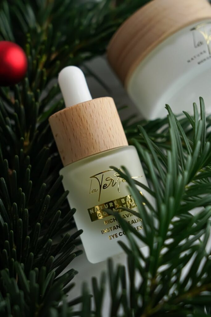 A bottle of natural eye cream amidst pine branches and festive decor, perfect for the holiday season.