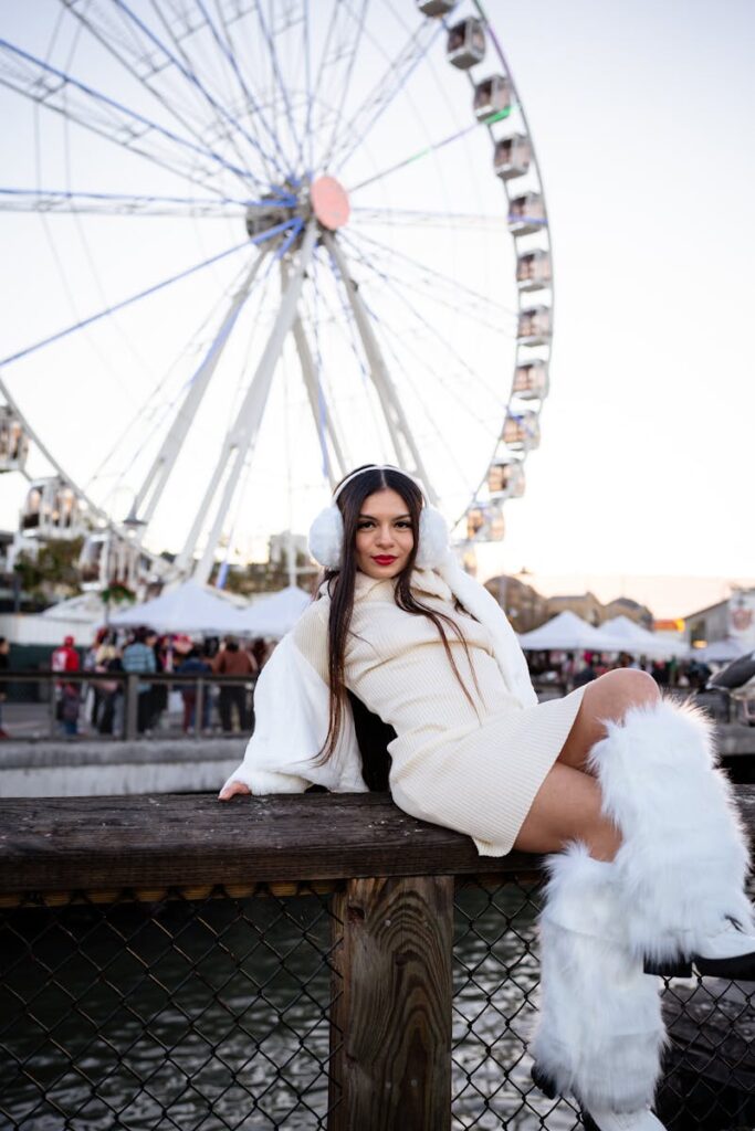 Stylish woman in winter attire poses by a Ferris wheel, showcasing chic urban fashion.
