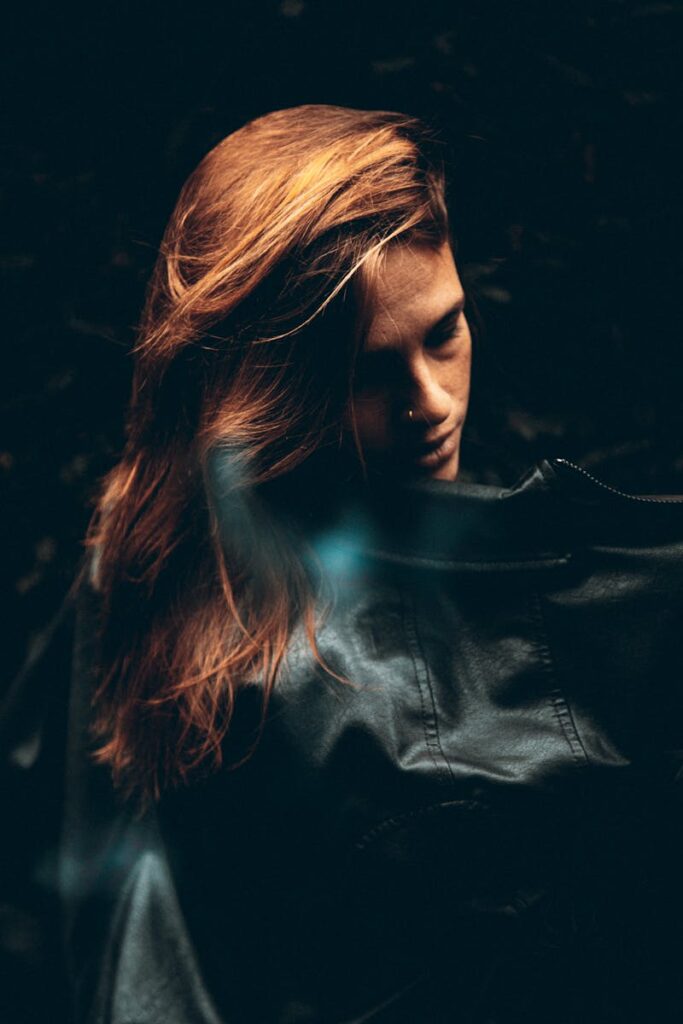 Artistic portrait of a woman with flowing hair in mysterious, moody lighting.