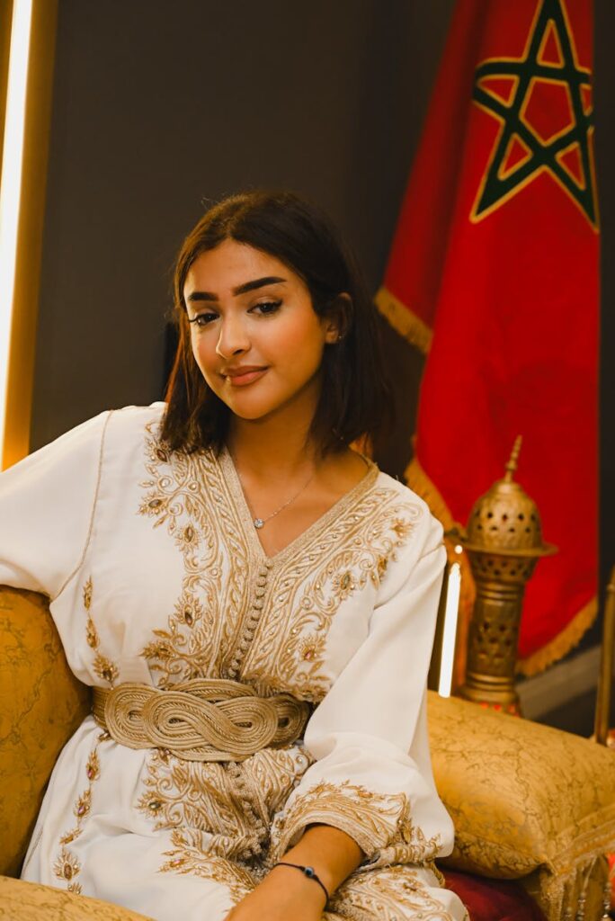 Young woman in white traditional Moroccan dress with flag background.