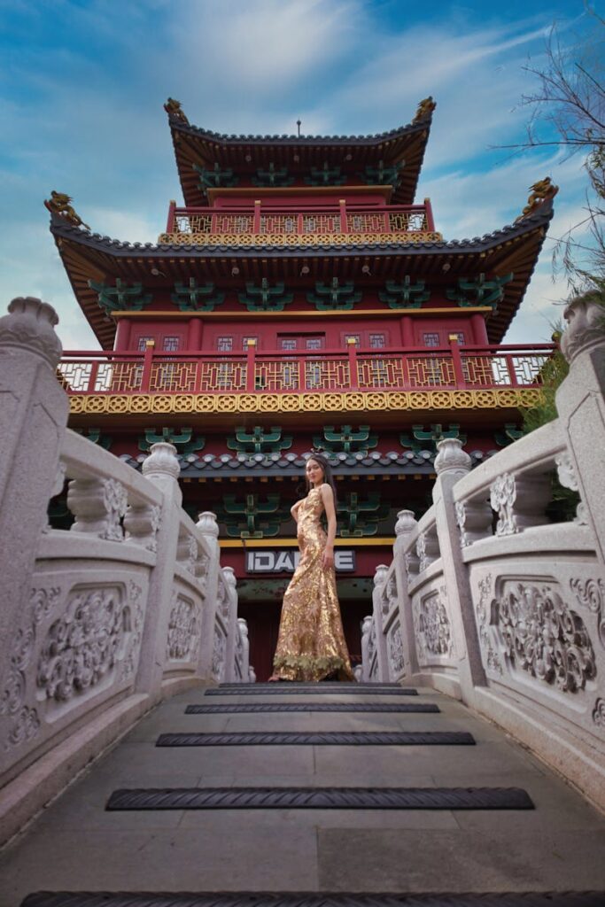 Woman in a gold dress posing at a Chinese pagoda in Jakarta. Stylish and cultural setting.