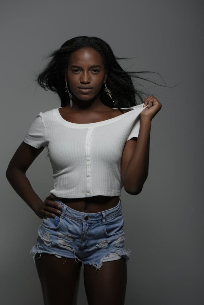 Confident young woman posing in trendy outfit with minimal background.