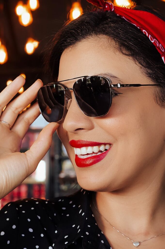 Confident woman with sunglasses and red bandana showcases a chic retro style.