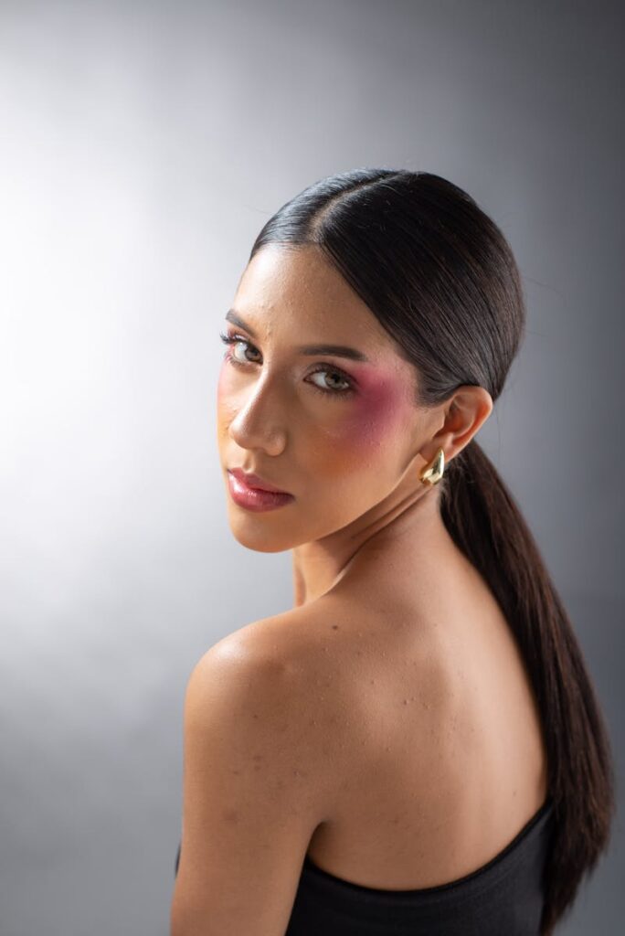 A striking portrait showcasing bold and vibrant makeup on a woman in a studio setting.