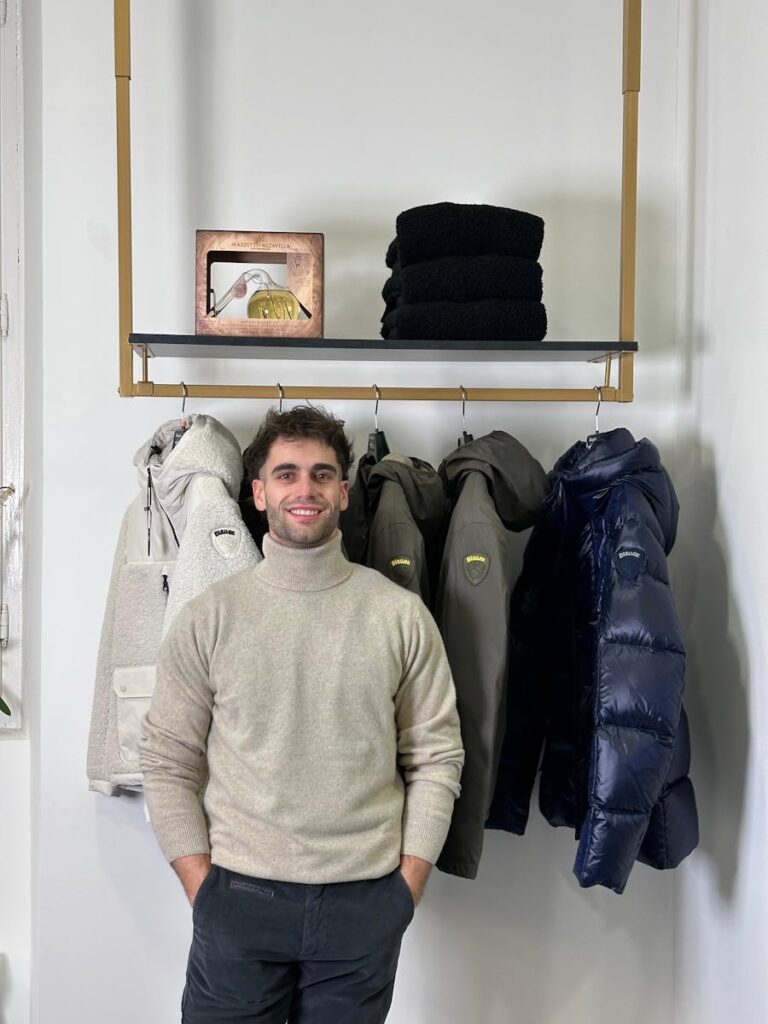 Man wearing a turtleneck standing by winter jackets on display.