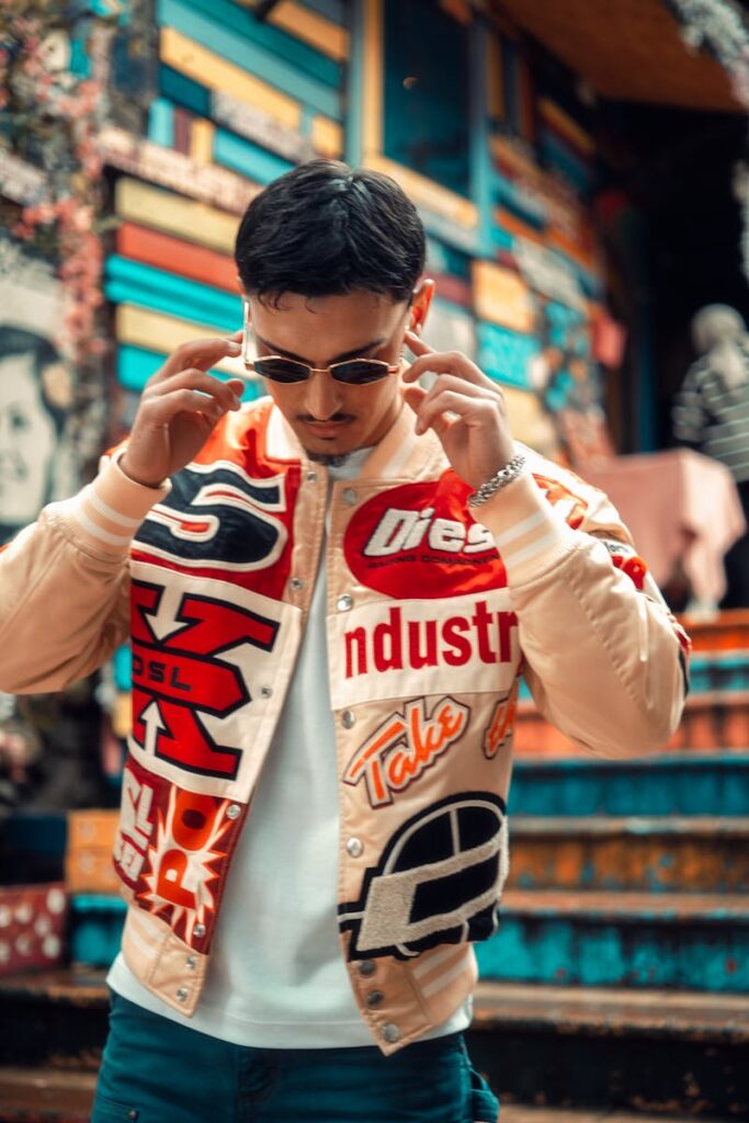 Man in stylish jacket adjusting sunglasses in a vibrant urban environment.