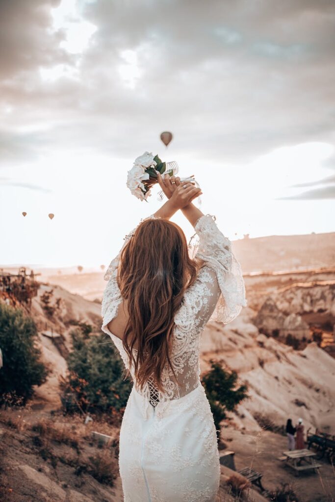 Bride holding bouquet with hot air balloons over Cappadocia, Turkey at sunset.